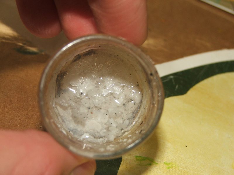 Granular white lithium hydroxide in a small glass jar